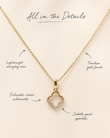 Gold necklace with clover pendant on a beige background