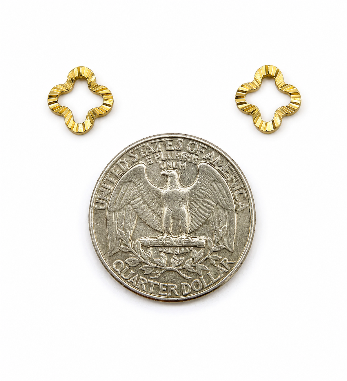 Gold flower-shaped earrings next to a US quarter for size reference