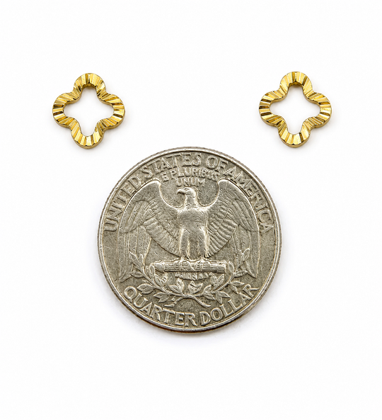 Gold flower-shaped earrings next to a US quarter for size reference