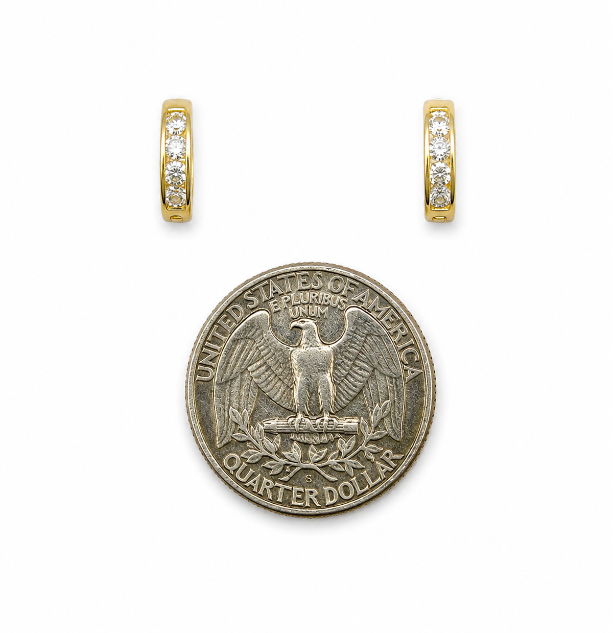 Gold huggie hoop earrings with pave stones next to a US quarter for size reference
