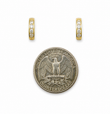 Gold huggie hoop earrings with pave stones next to a US quarter for size reference