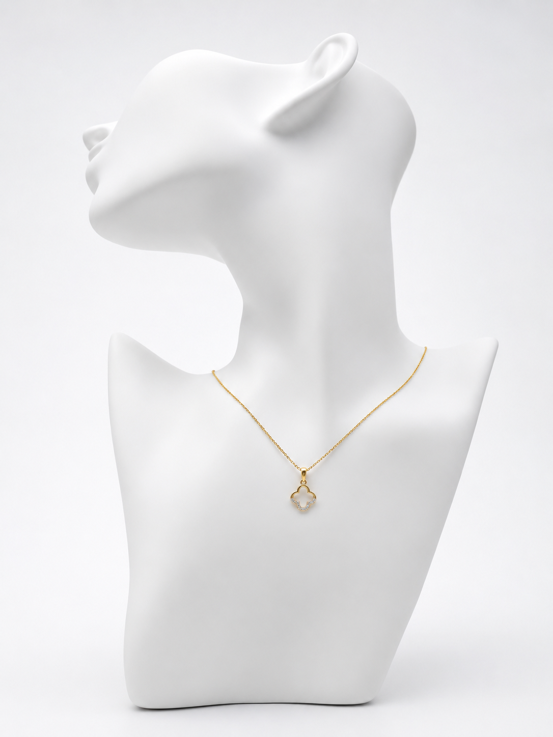 Gold necklace on a white mannequin bust against a white background