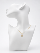 Gold necklace on a white mannequin bust against a white background