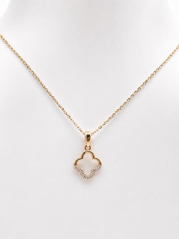 Gold necklace with a pave clover-shaped pendant on a white background